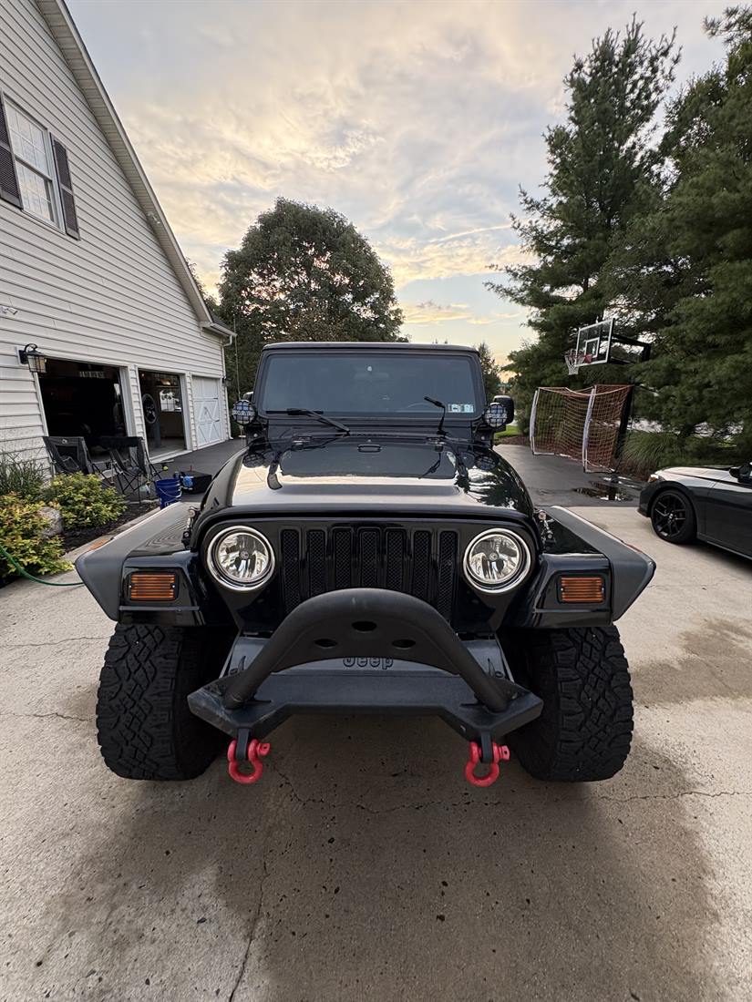 A Jeep being washed on site, buckets and hose in the driveway